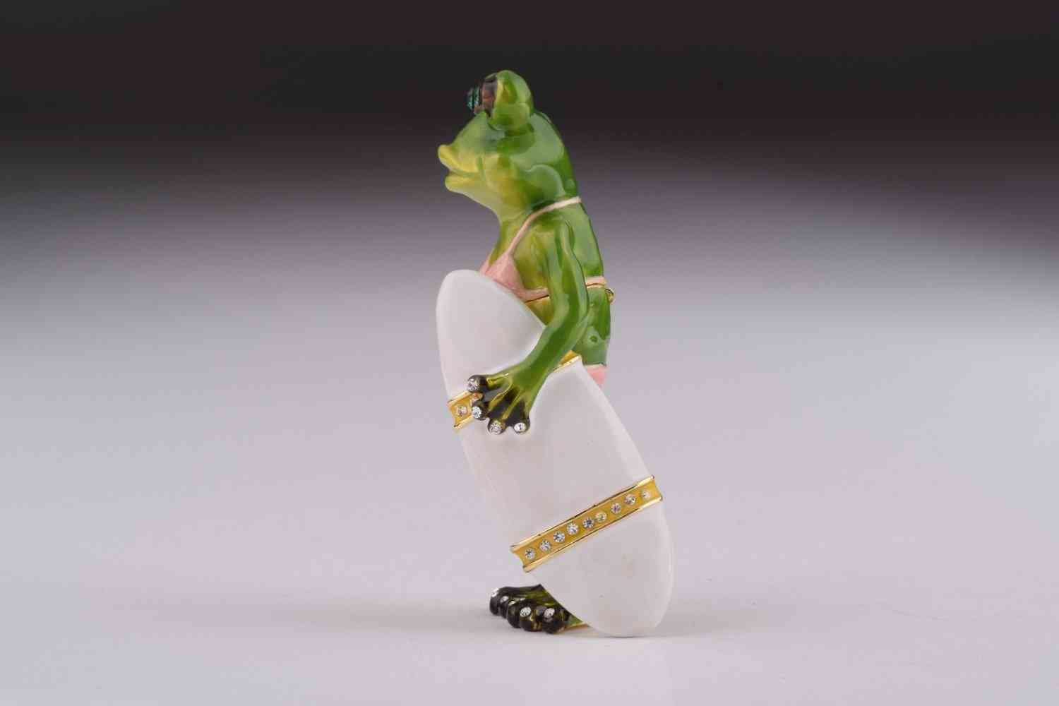 żaba trzyma pudełko bibelotów deski surfingowej