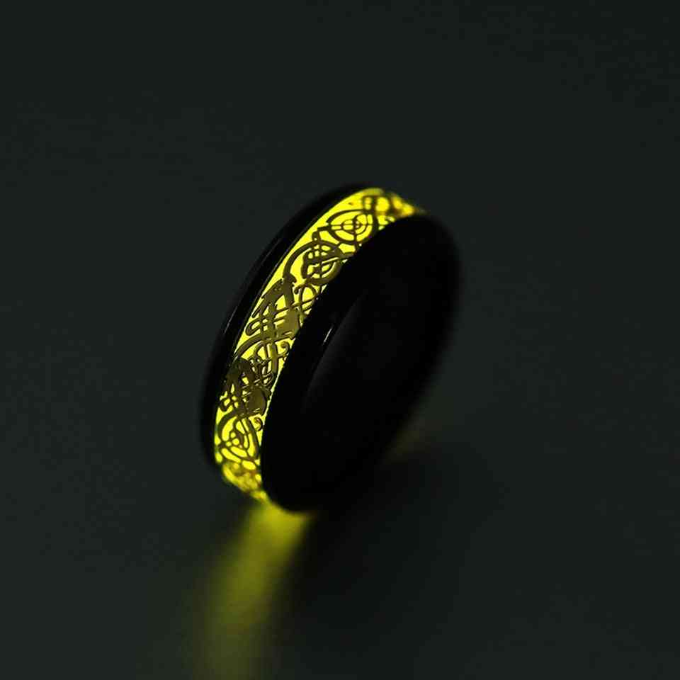 Dragon lumineux jaune brillant en acier inoxydable qui brille dans l'anneau sombre